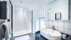 A modern bathroom with a large white sink, a glass shower enclosure, and a black vanity. - LA BICICLETA RAVITO (Souillac)