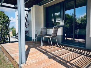 A covered patio with a table and chairs, large windows, and a view of greenery. - Apartment 1 Studio with Lake View (Reichenau)