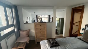 Une chambre à coucher avec un lit, un banc en bois, une commode et une fenêtre.