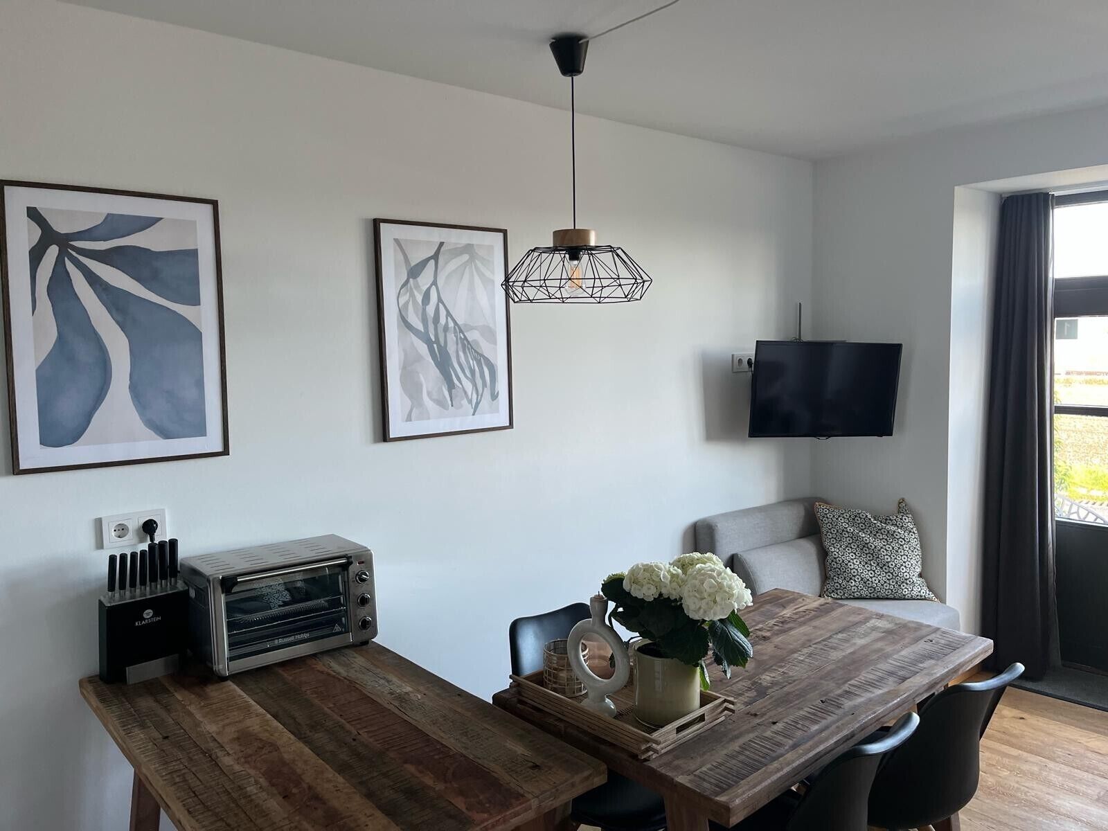 Eine moderne Küche mit einem Holztisch, einem Toaster und einem an der Wand montierten Fernseher.