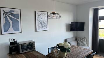 Eine moderne Küche mit einem Holztisch, einem Toaster und einem an der Wand montierten Fernseher.