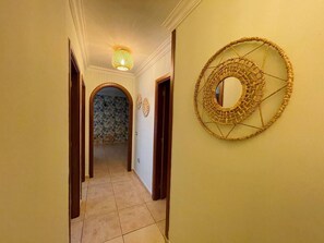 Ein Flur mit Wandverkleidung mit Muster, einer gewebten Wanddekoration und Fliesenboden.