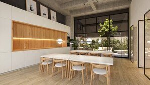 A modern conference room with a long table and chairs, wooden panel wall, and large windows overlooking a garden. - New, modern and comfortable in the best location (Bogotá)