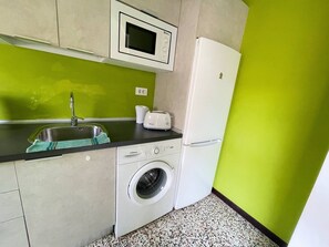 A compact kitchen with a sink, microwave, toaster, washing machine, and a refrigerator. - Canarias - modern apartment in the center (Playa De Los Cristianos)
