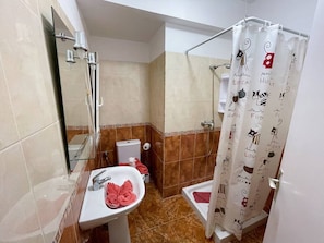 A bathroom with a glass shower enclosure, a white sink with a red towel, and a shower curtain with cat illustrations. - Sierra - in the center with big balcony (Playa De Los Cristianos)