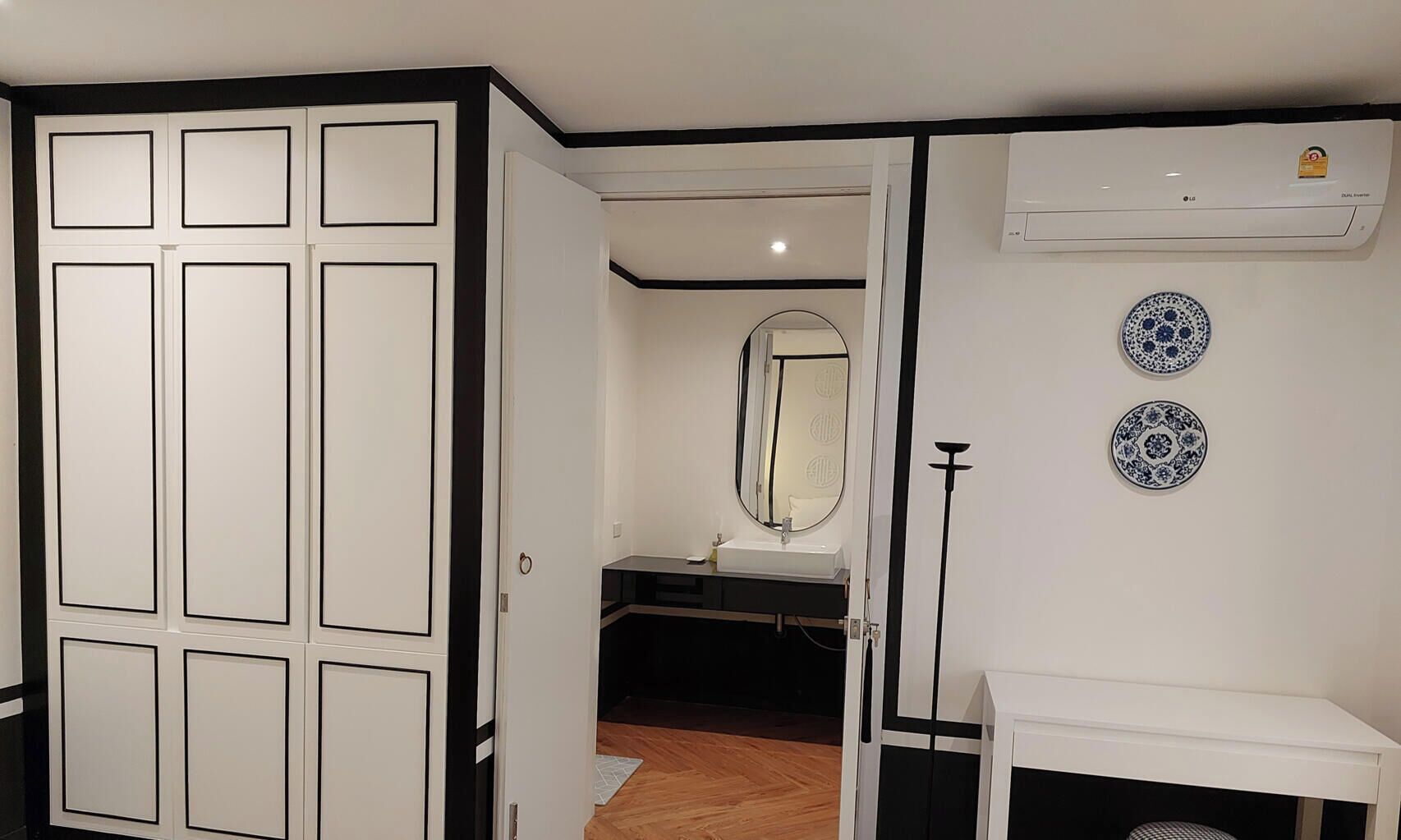A room with a wardrobe, a mirror, a sink, and decorative plates on the wall.