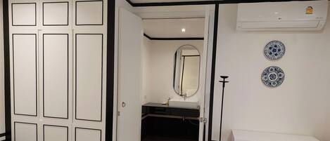 A room with a wardrobe, a mirror, a sink, and decorative plates on the wall.