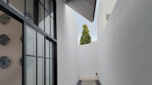 A narrow corridor with a glass door and windows, a small tree visible through a window, and a tiled floor. - Wild seaview pool 2bedroom villa 118 (Phuket)