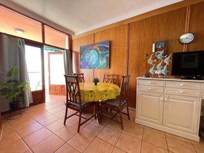 A dining area with a round table, chairs, a cabinet, and a painting on the wall. - CRISTIANMAR - closer to the sea imposible (Playa De Los Cristianos)
