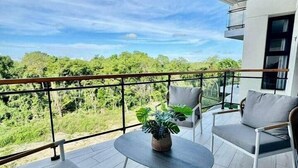 Un balcón con sofás grises, una mesita redonda y una planta en maceta.