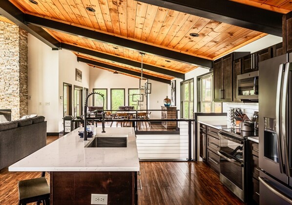A modern kitchen with a large island, stainless steel appliances, and a wooden ceiling. - Private Pool Cabin w/ Theater, Hot Tub & Views (Sevierville)