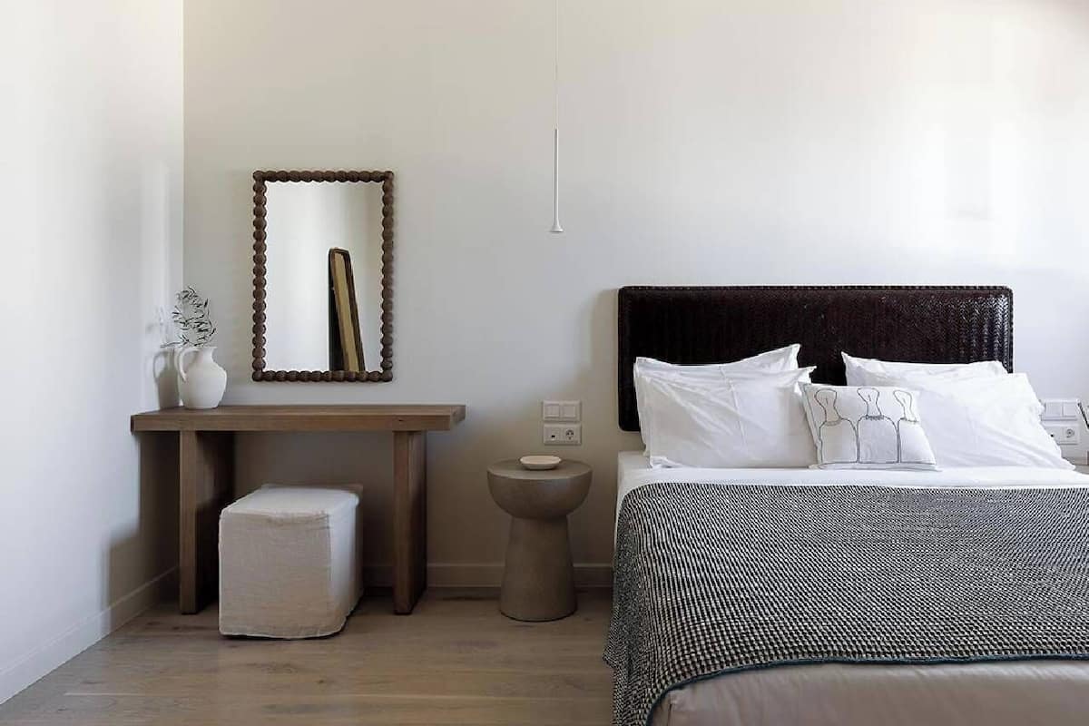Un dormitorio con cama, mesita de noche y espejo.