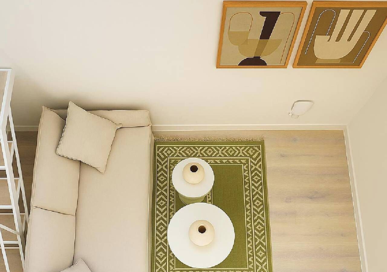 Ein Zimmer mit einem beigen Sofa, einem grün gemusterten Teppich und zwei Wandlampen.