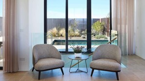 A room with two armchairs facing a large window overlooking a swimming pool and garden. - Lovely 2BR Villa with Pool in Cyprus (Tsada)