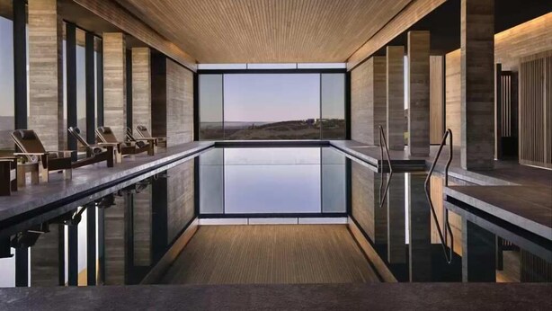 A modern indoor swimming pool with a clear view of the landscape, wooden ceiling, and lounge chairs along the poolside. - Lovely 2BR Villa with Pool in Cyprus (Tsada)