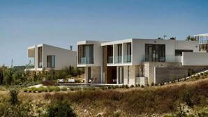 A modern multi-story house with a flat roof, large windows, and a stone facade. - Lovely 2BR Villa with Pool in Cyprus (Tsada)