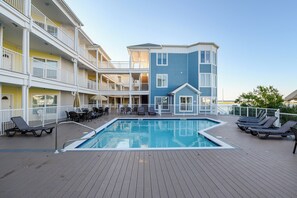 A multi-story hotel with a rooftop pool area, including lounge chairs and a dining area. - Sunset Bay Villa 320 by Seaside Vacations and Sales (Chincoteague Island)
