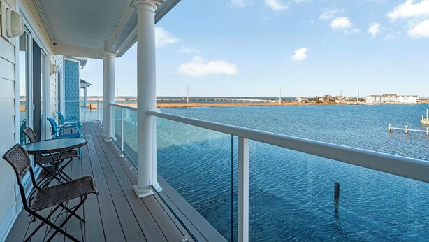 Un balcone con vista sull'acqua, con un tavolo e sedie.
