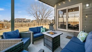An outdoor patio with wicker furniture, a fire pit, and a view of neighboring houses. - Cabin-Style Group Retreat Near RMNP, Lakes & Golf (Loveland)