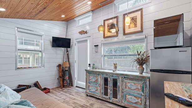 Een moderne keuken met een koelkast van roestvrij staal, een houten plafond en een groot raam met uitzicht op een terras.