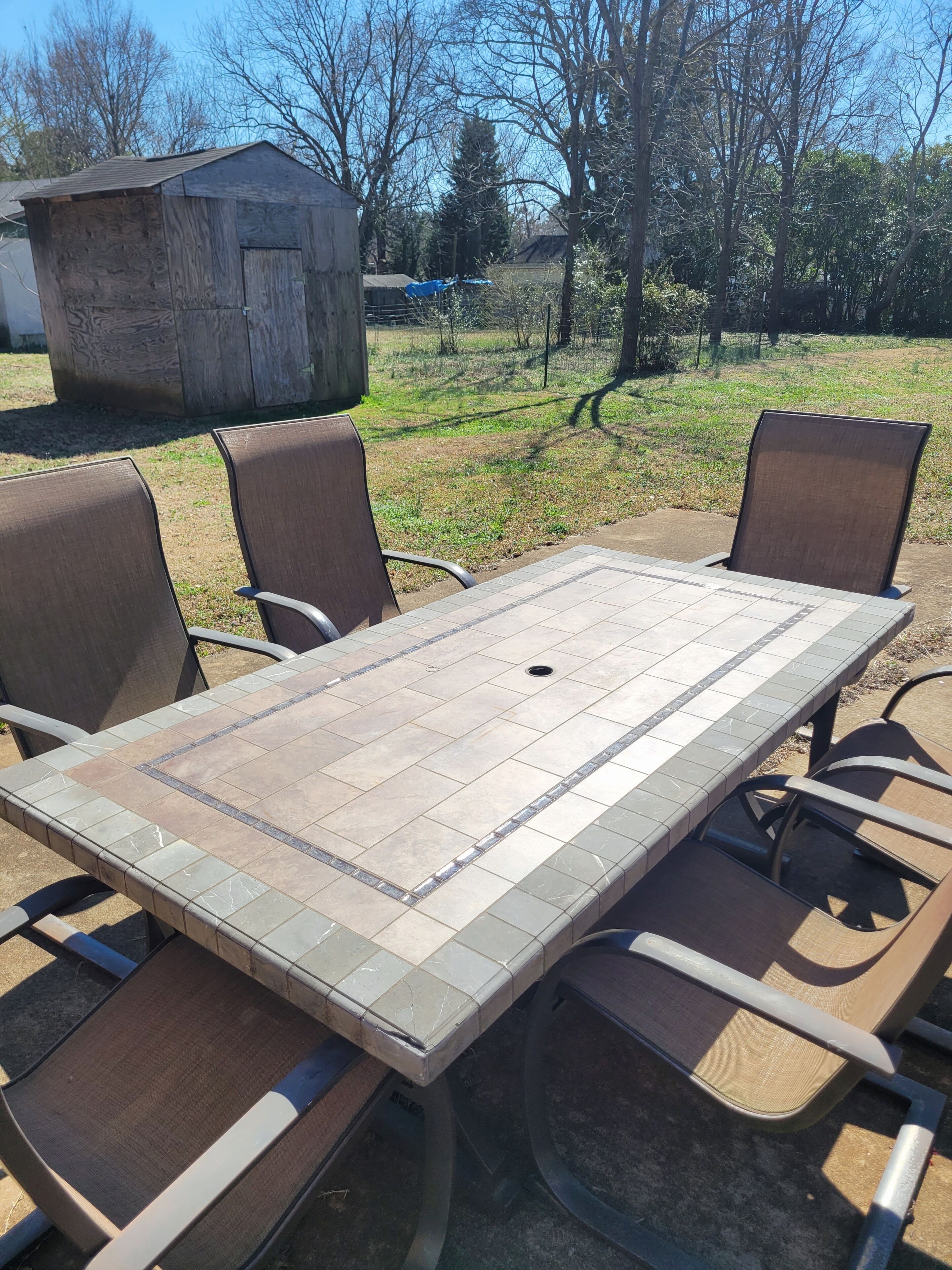 An outdoor dining area with a tiled table and four chairs.