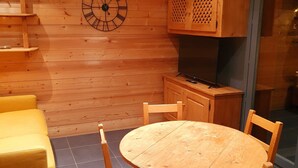 Un interior de madera con una mesa redonda, sillas, un sofá y un reloj en la pared.