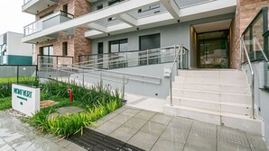 Un edificio moderno con un letrero que dice “MONIVERT”. Cuenta con una escalera, barandilla de vidrio y un pequeño jardín con plantas.