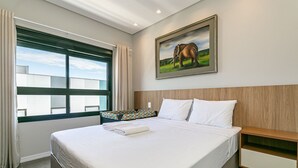 Una cama bien hecha con sábanas blancas, un cabecero de madera y una mesita de noche con cajón.