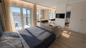 A modern hotel room with a large bed, a desk, a TV, and a balcony with a city view. - Riverside Luxury Studio AC, Balcony, Fast WIFI, Steps to Market Square (Wrocław)