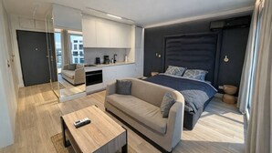 A modern hotel room with a bed, a sofa, a coffee machine, and a view of the city. - Riverside Luxury Studio AC, Balcony, Fast WIFI, Steps to Market Square (Wrocław)
