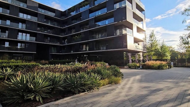 A modern multi-story residential building with balconies, a landscaped garden, and a paved driveway. - Riverside Luxury Studio AC, Balcony, Fast WIFI, Steps to Market Square (Wrocław)