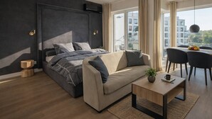 A modern bedroom with a bed, sofa, and a dining area with chairs. - Riverside Luxury Studio AC, Balcony, Fast WIFI, Steps to Market Square (Wrocław)