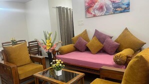 A living room with a sofa, two armchairs, a coffee table, and a floral arrangement. - Premium 2BHK• Clean & Central • Walk to IT Hub (Hyderabad)