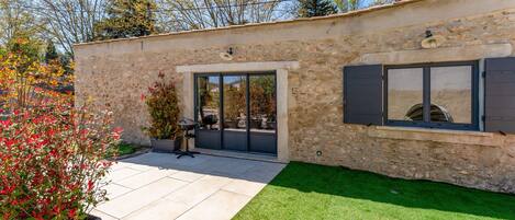 A stone building with a glass door, a potted plant, and a well-maintained lawn.