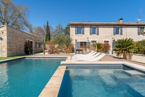 A swimming pool with a stone building in the background. - Holiday Home 'Daudet - Stone Mas' with Shared Pool, Wi-Fi & Air Conditioning (Saint-Rémy-de-Provence)