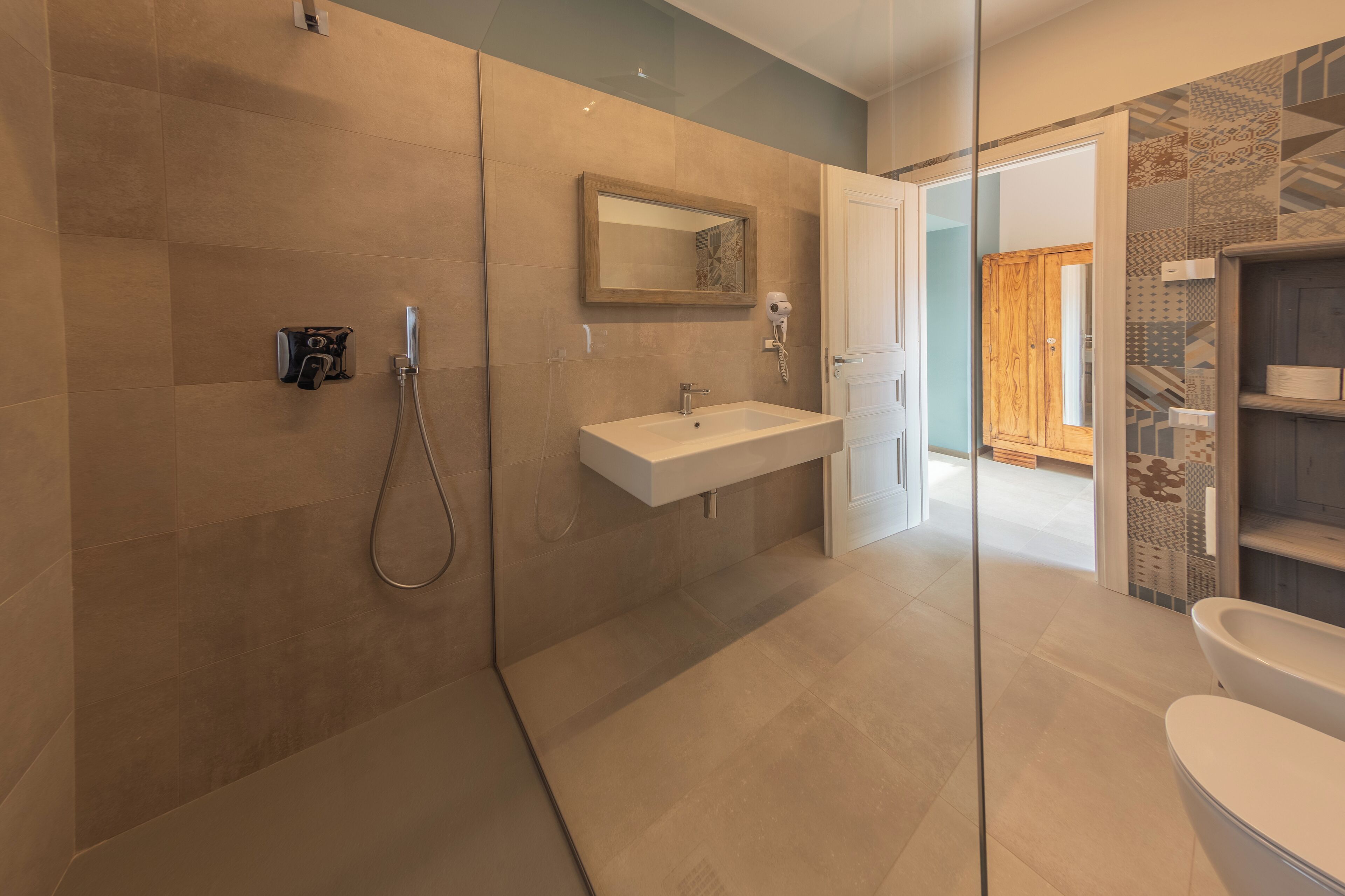 A modern bathroom with a glass shower enclosure, a white sink, and a wooden cabinet.