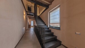 A modern interior with a staircase leading to an upper floor, a window with blinds, and a light switch on the wall. - La Casa di Caterina (Atripalda)
