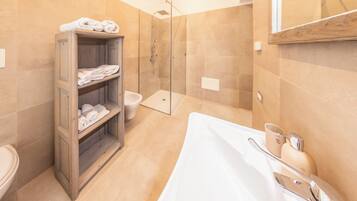 Une salle de bain moderne avec une douche à parois de verre, un porte-serviettes en bois et une baignoire blanche.
