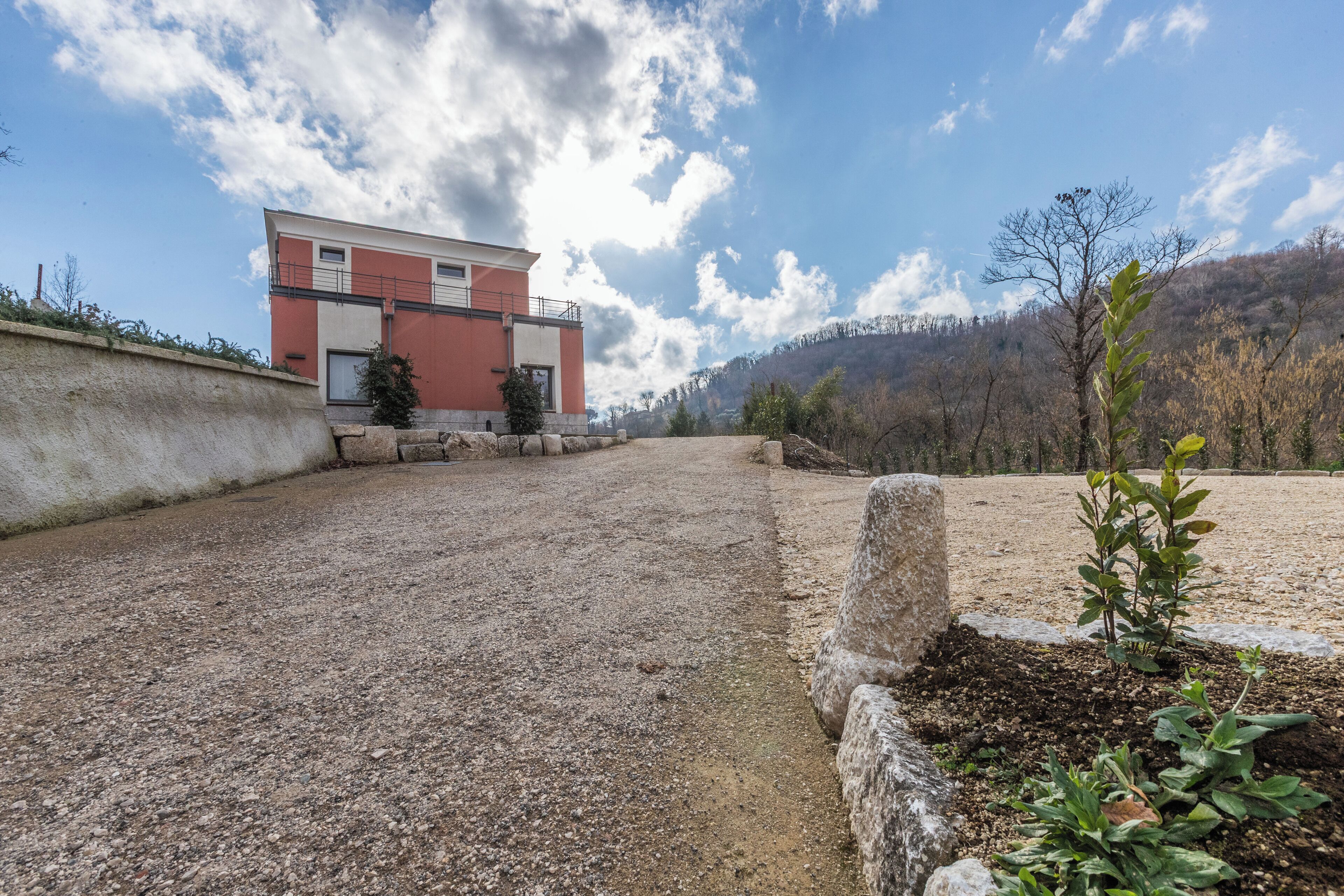 A building with a red and white facade, a gravel driveway, and a mountainous backdrop.