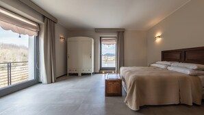A bedroom with a large bed, a wardrobe, a small table, and a view of the outdoors through a window. - La Casa di Caterina (Atripalda)