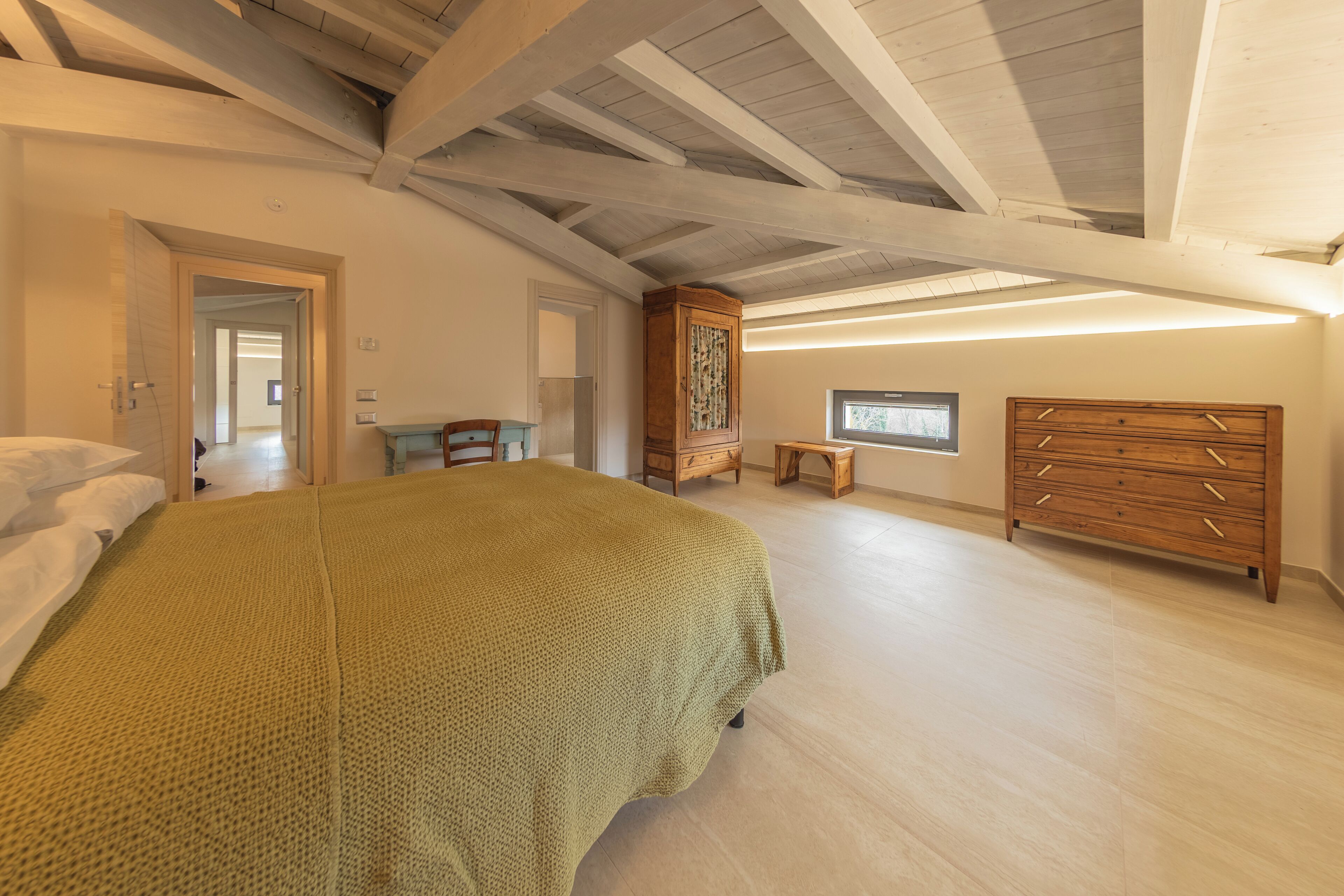 A bedroom with a large bed, wooden dresser, and a small table.