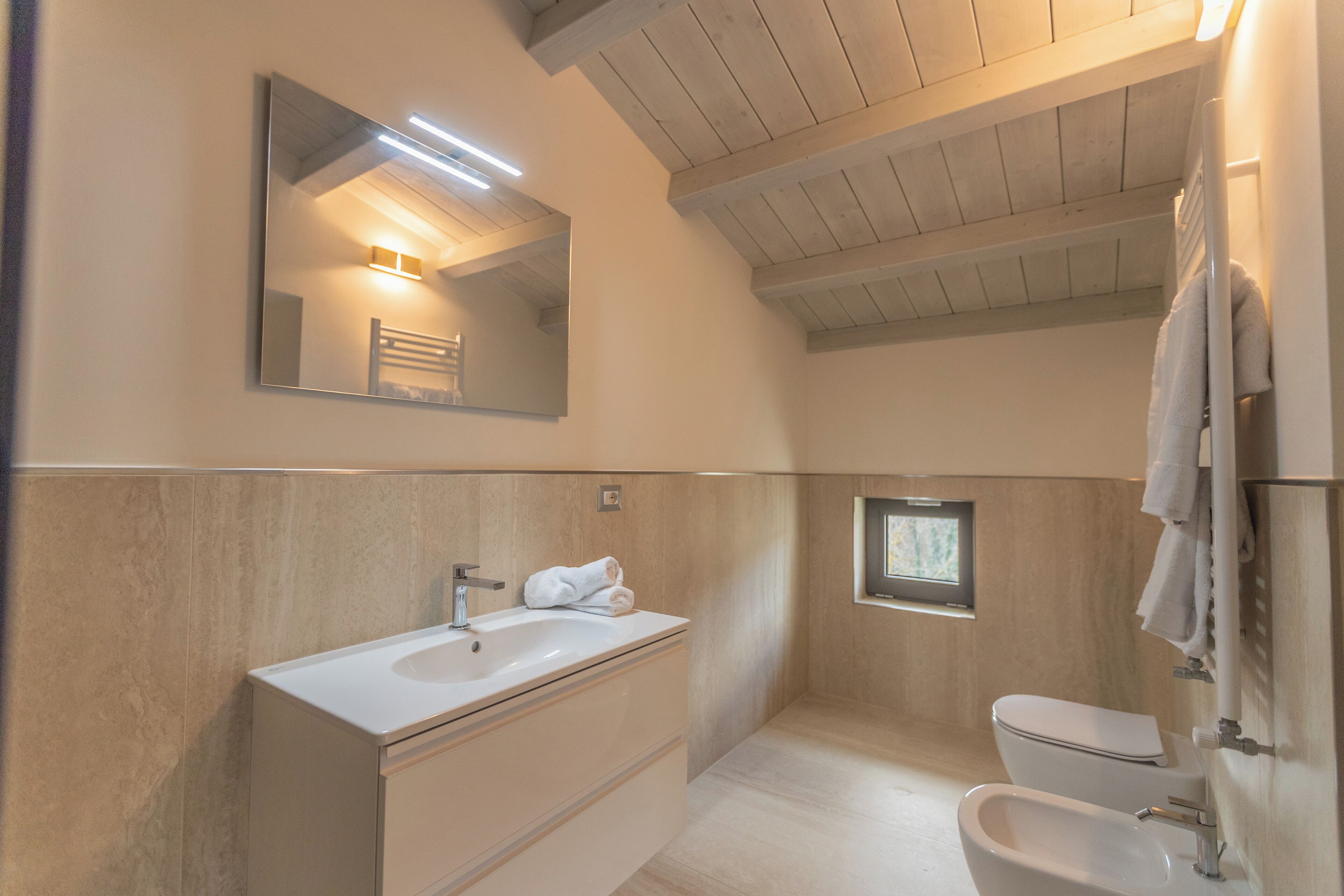 Un baño moderno con un espejo grande, un lavabo, un inodoro y un bidé.
