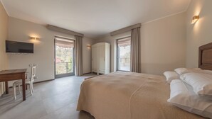 A hotel room with a bed, a desk, chairs, a TV, and a wardrobe. - La Casa di Caterina (Atripalda)