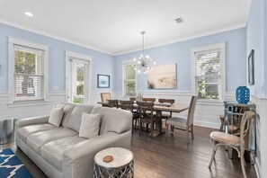 A dining area with a wooden table and chairs, a chandelier, and a painting on the wall. - 🚲 Sail & Trails | Golf Cart + 4 Bikes | Pet Friendly | 30A (Santa Rosa Beach)