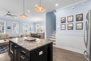 A modern kitchen with a marble island, pendant lighting, and a dining area with a staircase. - 🚲 Sail & Trails | Golf Cart + 4 Bikes | Pet Friendly | 30A (Santa Rosa Beach)