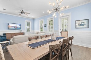 A dining area with a long wooden table, chairs, and a ceiling fan. - 🚲 Sail & Trails | Golf Cart + 4 Bikes | Pet Friendly | 30A (Santa Rosa Beach)