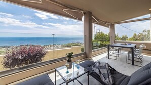 A balcony with a table and chairs, a sofa, and a view of the sea. - Blue Horizon Villa (Kalyvia Thorikou)
