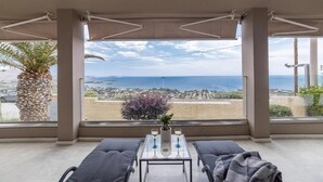 A balcony with a view of the sea and a cityscape, furnished with a table and two chairs, and a potted plant. - Blue Horizon Villa (Kalyvia Thorikou)