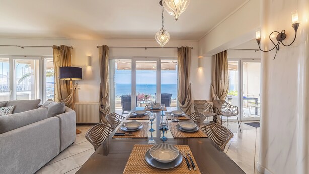 A modern dining room with a large table set for six, surrounded by chairs. - Blue Horizon Villa (Kalyvia Thorikou)