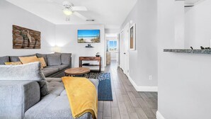 A modern living room with a gray sofa, a wooden coffee table, and a TV mounted on the wall. - 🏖️Easy Beach Access | Family Friendly | Sand Castles West II G3- Castawave🏖️ (Panama City Beach)